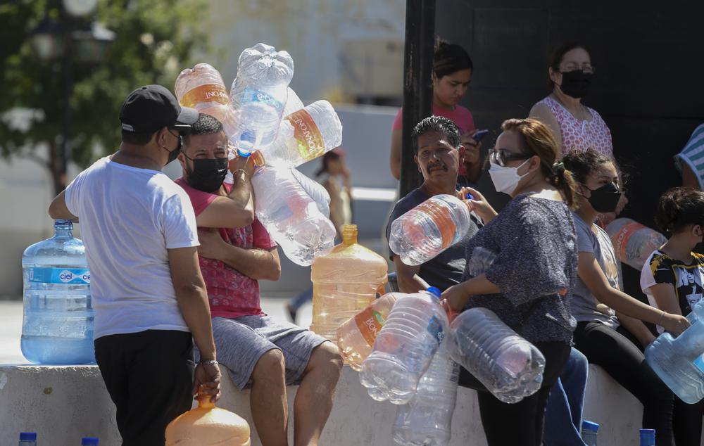 Vecinos esperan para llenar garrafas de plástico con agua, en un punto de suministro público en Monterrey, México, el 20/6/2022
