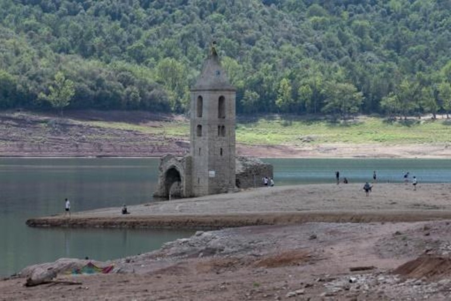 arias personas se acercan a las ruinas de la iglesia románica de Sant Romà de Sau, a la vista por el bajo nivel del agua en el pantano de Sau en la provincia catalana de Girona, al noreste de España