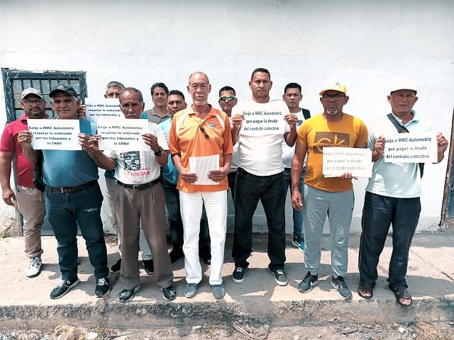 Trabajadores de MMC Automotríz con carteles de protesta